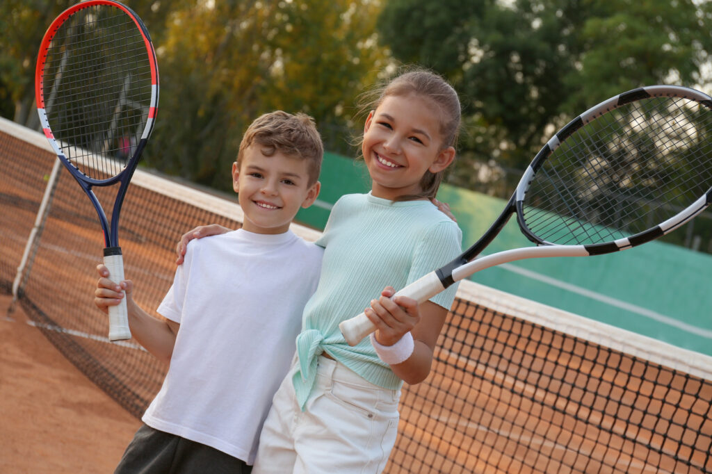 Glückliche Kinder mit Tennisschlägern im Freien