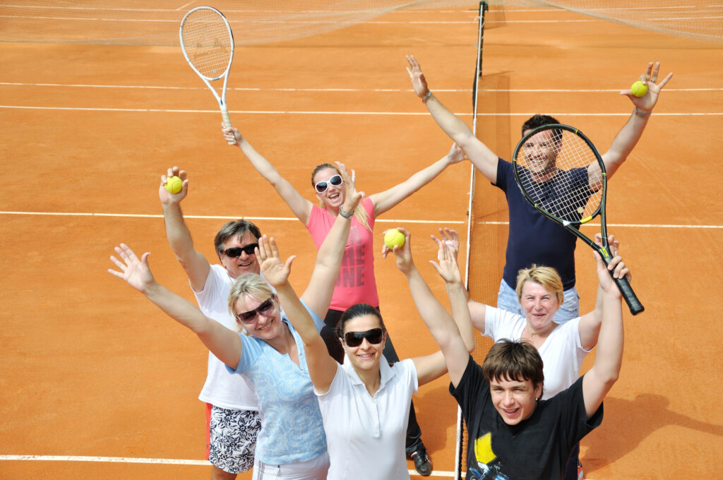 7 glückliche Freunde auf dem Tennisplatz